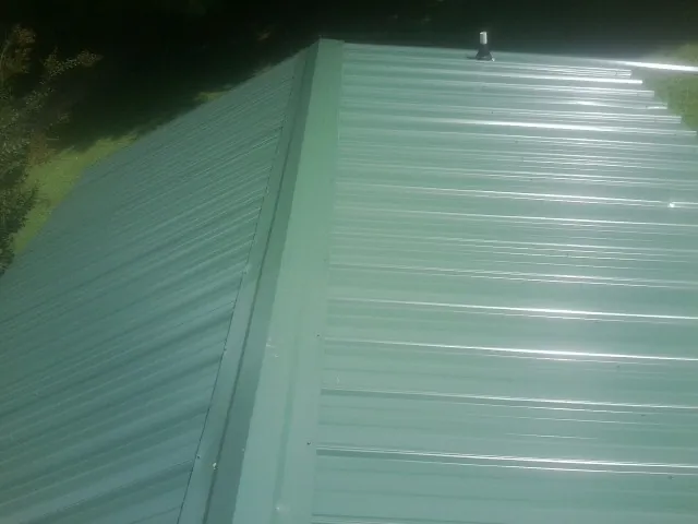 New green metal panels meeting at the ridge of a roof — Flat Roof Repair work by our crew in Kennard