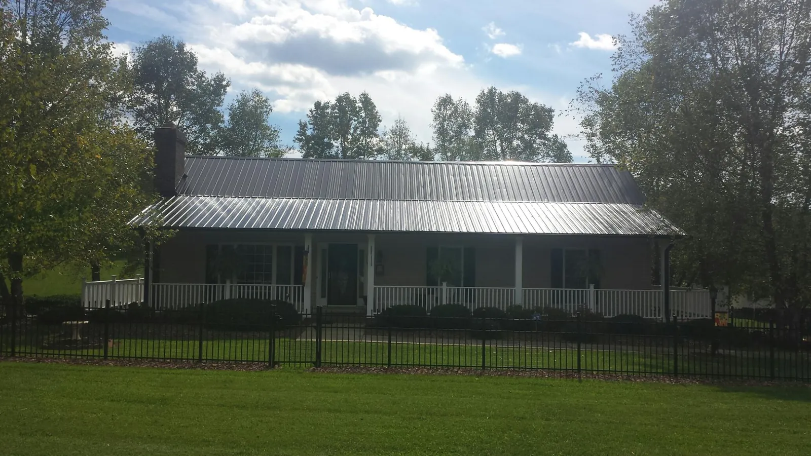Gray metal roof on a brick ranch with a full width front porch — Gutter Guard Installation work by our crew in Kennard
